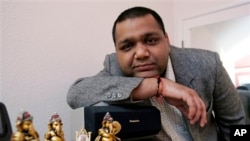 Gautam Aggarwal, a software engineer from India working for a Silicon Valley startup, poses with Indian god figures on his television set at his home in Mountain View, California.