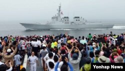한국 해군작전사령부가 22일 마련한 '제63주년 대한해협 해전 전승기념 함정공개·항해체험' 행사에 참가한 시민들이 대형수송함 독도함을 타고 해상사열을 보고 있다.