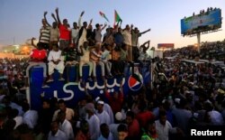 Sudanese demonstrators chant slogans as they attend a mass anti-government protest outside Defence Ministry in Khartoum, April 21, 2019.