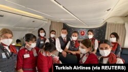 Awak kabin Turkish Airlines berpose dengan bayi perempuan Afghanistan yang baru lahir bernama Havva di dalam penerbangan evakuasi dari Dubai ke Birmingham Inggris, 28 Agustus 2021. (Foto: Turkish Airlines via REUTERS)