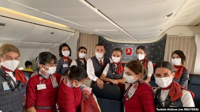 Awak kabin Turkish Airlines berpose dengan bayi perempuan Afghanistan yang baru lahir bernama Havva di dalam penerbangan evakuasi dari Dubai ke Birmingham Inggris, 28 Agustus 2021. (Foto: Turkish Airlines via REUTERS)