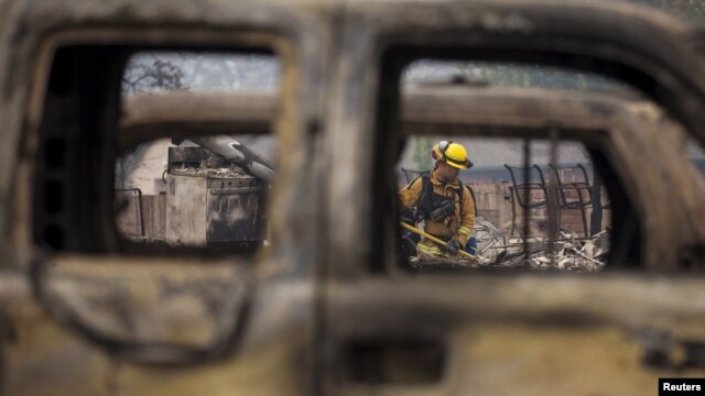 Un bombero visto a través de un auto destruido por las llamas en Middletown, California.
