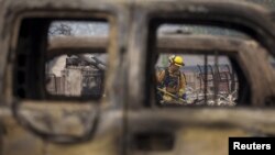 Un bombero visto a través de un auto destruido por las llamas en Middletown, California.