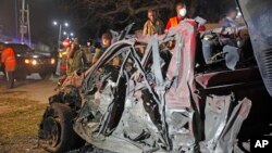 Soldiers stand near the wreckage of a suicide car bomb outside Somalia's presidential palace, Sept, 21, 2015.