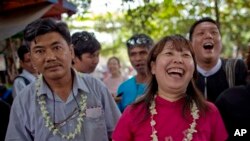 Myanmar civic rights activists Soe Moe Tun (l) and Ma Tandar, both wearing flower- garlands, laugh outside prison after receiving a presidential pardon in the suburbs of Yangon, Myanmar, Dec. 11, 2013.