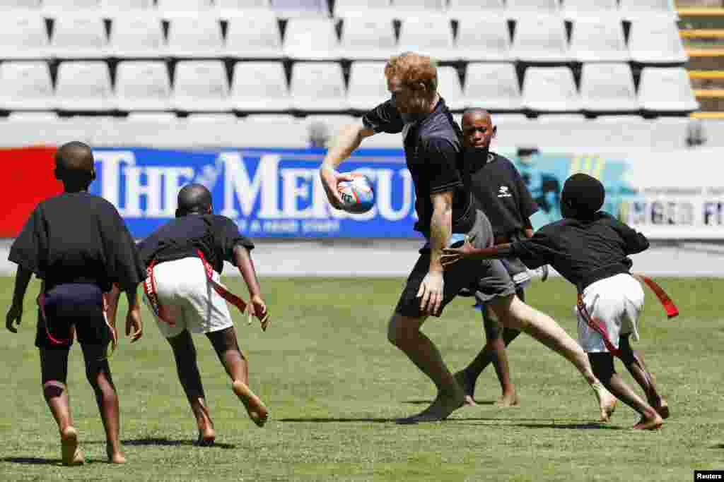 Pangeran Harry bermain tag rugby bersama anak-anak setempat saat latihan di Durban, Afrika Selatan. Pangeran Harry berada di Afrika Selatan sebagai perwakilan dari Sentebale, badan amal yang ia dirikan bersama Pangeran Seeiso dari Lesotho untuk mengenang ibu mereka.