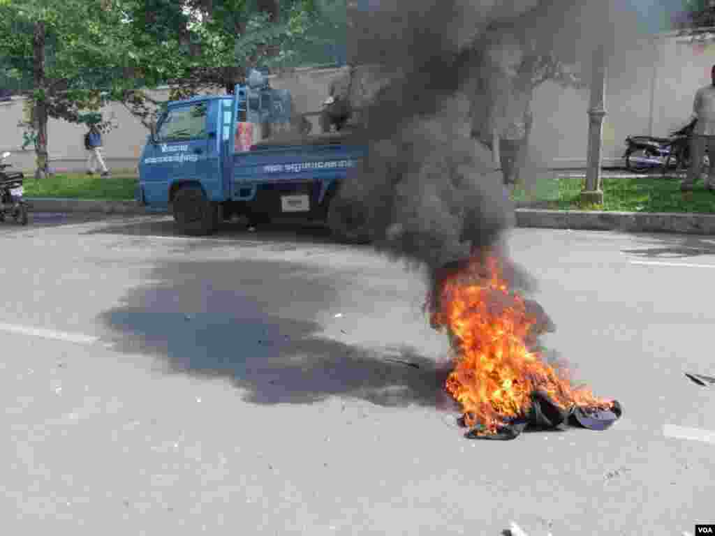 Angry protesters set fire to clothes belonging to security guards after the guards left them and fled the scene, Phnom Penh, Cambodia, July 15, 2014. (Khoun Theara/VOA)