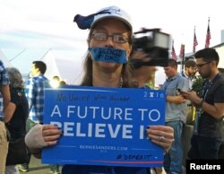 FILE - A Bernie Sanders supporter hold up a signs during an improvised protest in front of the media tents on Day 2 of the Democratic National Convention at the Wells Fargo Center in Philadelphia, Pennsylvania, July 26, 2016.