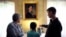 FILE - Museum visitors stand near a portrait of author Louisa May Alcott by American artist George Healy at Orchard House, in Concord, Mass., May 17, 2018. 