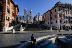 A person sits next to the Barcaccia fountain with Spanish steps in the background, as Italy goes back to lockdown as part of efforts put in place to curb the spread of the coronavirus disease (COVID-19), in Rome, Dec. 31, 2020.