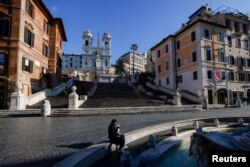 A person sits next to the Barcaccia fountain with Spanish steps in the background, as Italy goes back to lockdown as part of efforts put in place to curb the spread of the coronavirus disease (COVID-19), in Rome, Dec. 31, 2020.