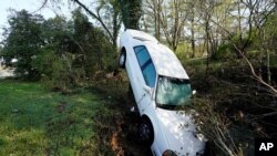 A car that was carried by floodwaters leans against a tree in a creek, March 28, 2021, in Nashville, Tenn.