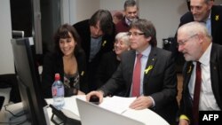 FILE - Axed Catalan president Carles Puigdemont flanked by deposed government's members looks on a computer at the results of the Catalonia's regional elections, at the Square - Brussels Meeting Centre in Brussels on Dec. 21, 2017. 