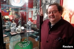 French Beatles specialist and collector Jacques Volcouve, one of the world's greatest living experts of the band, poses next to figurines on stage at Drouot auction house in Paris, March 16, 2017, a part of the 15,000 items going on sale on next March 18.