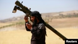 FILE - An Islamist Syrian rebel group Jabhat al-Nusra fighter talks on a walkie-talkie while carrying his weapon on Al-Khazan frontline of Khan Sheikhoun, northern Idlib province, Syria, May 17, 2014. 