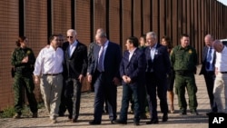 Presiden Joe Biden berbicara dengan anggota parlemen AS, Henry Cuellar (kedua dari kiri), saat mereka berjalan di sepanjang perbatasan AS-Meksiko di El Paso Texas, Minggu, 8 Januari 2023. (AP/Andrew Harnik)
