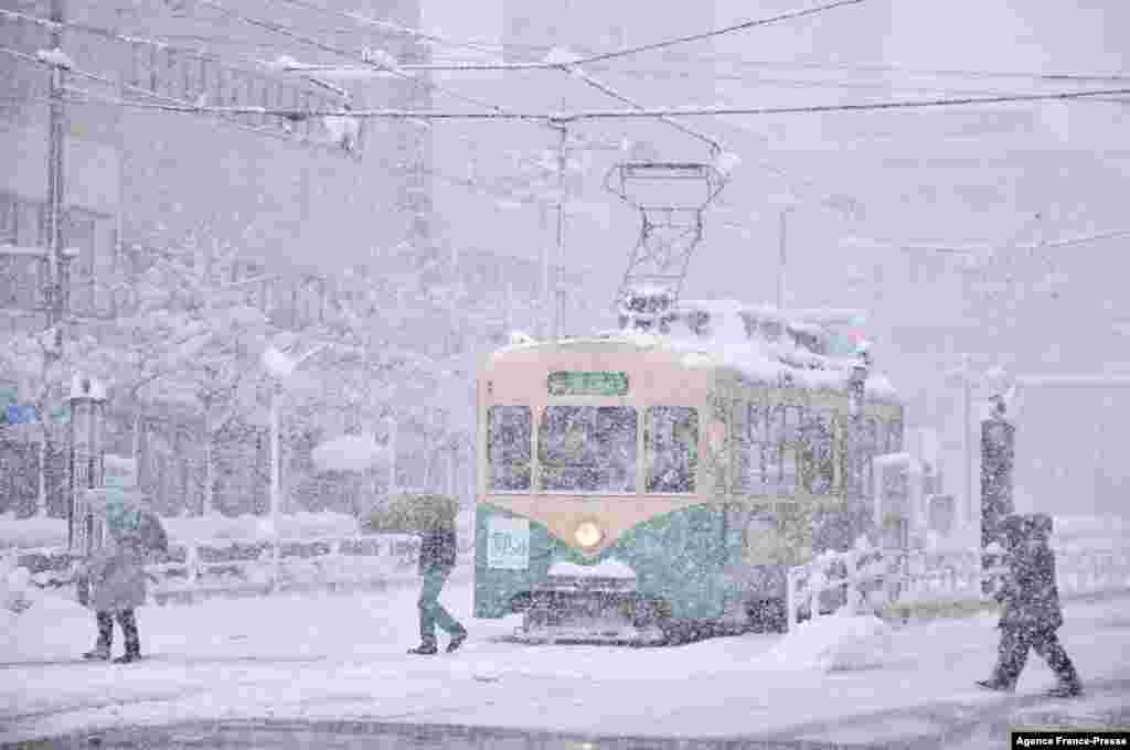 People cross a street in heavy snow in the city of Toyama, Toyama prefecture, brought by an extreme cold front along western and northern parts of Japan.