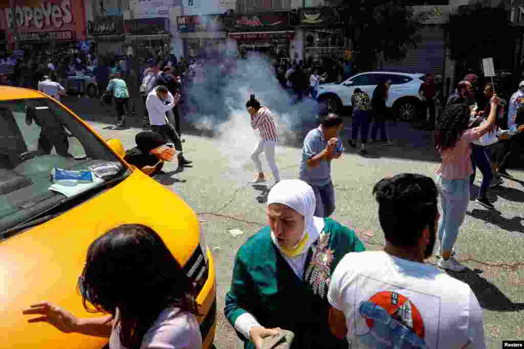 Demonstrators react to tear gas during clashes with Palestinian security forces at a protest following the death of Nizar Banat, a Palestinian parliamentary candidate who criticized the Palestinian Authority and died after being arrested by PA forces, in Ramallah in the Israeli-occupied West Bank.