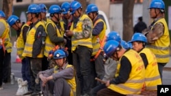 资料照片: 2024年4月9日北京: 工人们在建筑工地外等车