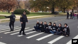 FILE - People sit in a street in Hartford, Conn., Nov. 27, 2017, to protest the handling of the case of Jayson Negron, 15, killed by police in May in Bridgeport. A reporter was detained Thursday, during a demonstration marking the two-year anniversary of the shooting.