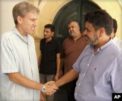 FILE – The late U.S. Ambassador to Libya Chris Stevens, left, greets a Libyan man in this photo posted on the U.S. Embassy Tripoli Facebook page on Aug. 27, 2012.