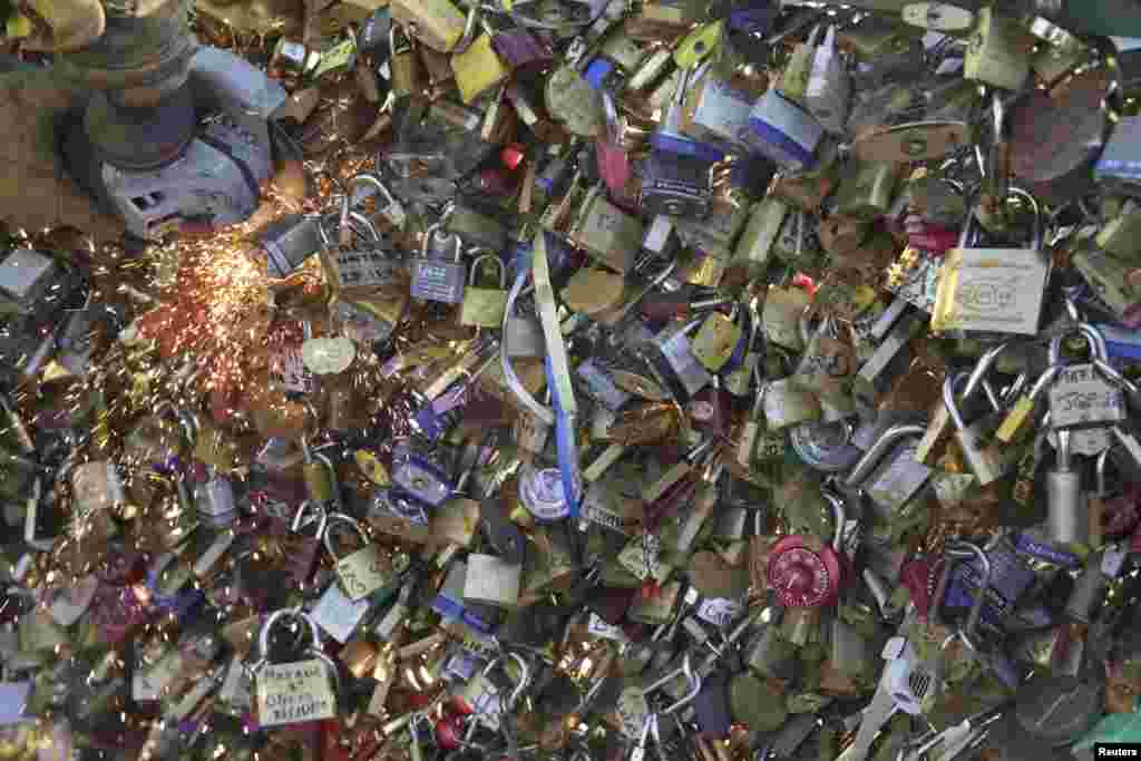 An employee of Paris city Hall removes padlocks clipped by lovers on the fence of the Pont des Arts over the River Seine in Paris, France. About 700,000 love locks are added every few months and officials say they are damaging the bridges and threatening safety because of the added weight.