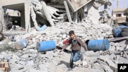 FILE - A boy runs over rubble at a site hit by what activists say were airstrikes by forces loyal to Syria's President Bashar al-Assad in the rebel-controlled area of Deir al-Asafir town, near Damascus, March 11, 2015. 