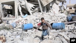 FILE - A boy runs over rubble at a site hit by what activists say were airstrikes by forces loyal to Syria's President Bashar al-Assad in the rebel-controlled area of Deir al-Asafir town, near Damascus, March 11, 2015. 