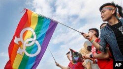 FILE - Supporters of LGBT wave rainbow flags during a rally supporting a proposal to allow same-sex marriage, in Taipei, Taiwan, Dec. 10, 2016.