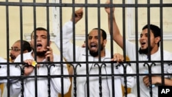 Supporters of the Muslim Brotherhood and other Islamists call out from the defendants cage as they receive sentences ranging from death by hanging for one, life in prison for 13 and 8-15 years for the others after they were convicted of murder, rioting, and violence in a mass trial in Alexandria, Egypt, May 19, 2014.