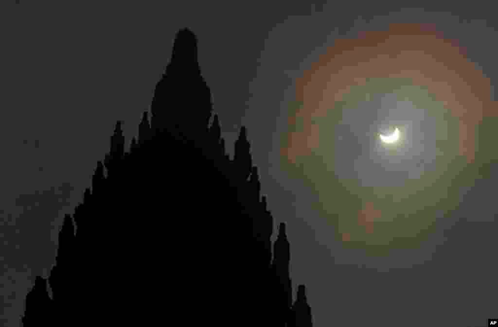 Gerhana matahari sebagian terlihat di latar belakang Candi Prambanan di Yogyakarta (9/3). (AP/Slamet Riyadi)