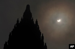 A partial solar eclipse is seen behind the 9th century Prambanan Temple in Yogyakarta, Indonesia, Wednesday, March 9, 2016.