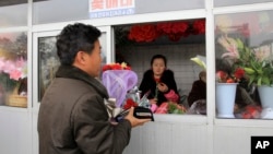FILE - A North Korean man purchases a bouquet of carnations at a flower stand in the Mansudae District of downtown Pyongyang, North Korea.