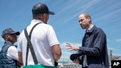 El príncipe Guillermo de Gran Bretaña, a la derecha, habla con un pescador local en el puerto de Kalk Bay, cerca de Ciudad del Cabo, Sudáfrica, el jueves 7 de noviembre de 2024. AP