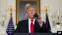 President Donald Trump adjusts the microphone to speak about the partial government shutdown, immigration and border security in the Diplomatic Reception Room of the White House, in Washington, Jan. 19, 2019. 