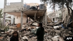 巴勒斯坦儿童站在加沙拉法地区被以色列炸毁房屋的废墟中。（2024年1月27日）