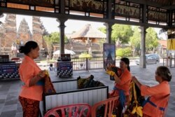 Para pedagang perempuan menyiapkan kain sarung menunggu wisatawan yang sepi di Candi Puseh, Desa Batuan, Gianyar, Bali (5/2).