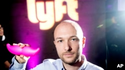 Foto Logan Green, salah satu pendiri dan CEO Lyft, menunjukkan logo perusahaannya "glowstache" atau kumis yang berkilau dalam sebuah acara peluncuran di San Francisco. Pada hari Senin, 4 Januari 2016, General Motors Co. mengumumkan investasinya pada Lyft sebesar $500 juta.