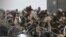 Tentara AS berjaga di balik kawat berduri saat warga Afghanistan duduk di pinggir jalan dekat bagian militer bandara di Kabul pada 20 Agustus 2021. (Foto: AFP/Wakil Kohsar)