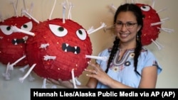 In this photo provided by Alaska Public Media, Carolina Tolladay Vidal displays custom COVID-19 piñatas in her home in Anchorage, Alaska, on April 14, 2021. (Hannah Lies/Alaska Public Media via AP)