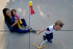 FILE - Claire Reagan plays with her kids Evan, 5, and Abbie, 3, outside her home in Olathe, Kansas, Sept. 21, 2020. Reagan is keeping her son from starting kindergarten and her daughter from preschool due to concerns about the coronavirus pandemic.
