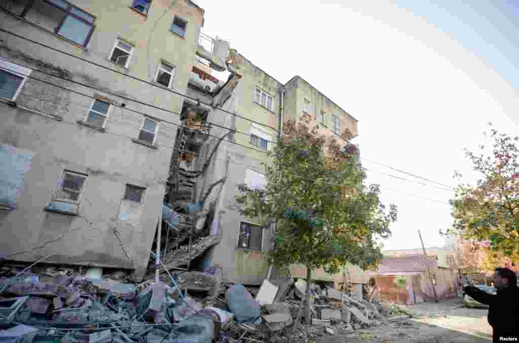 A man takes pictures of a damaged building in Durres, after an earthquake shook Albania, Nov. 26, 2019. 