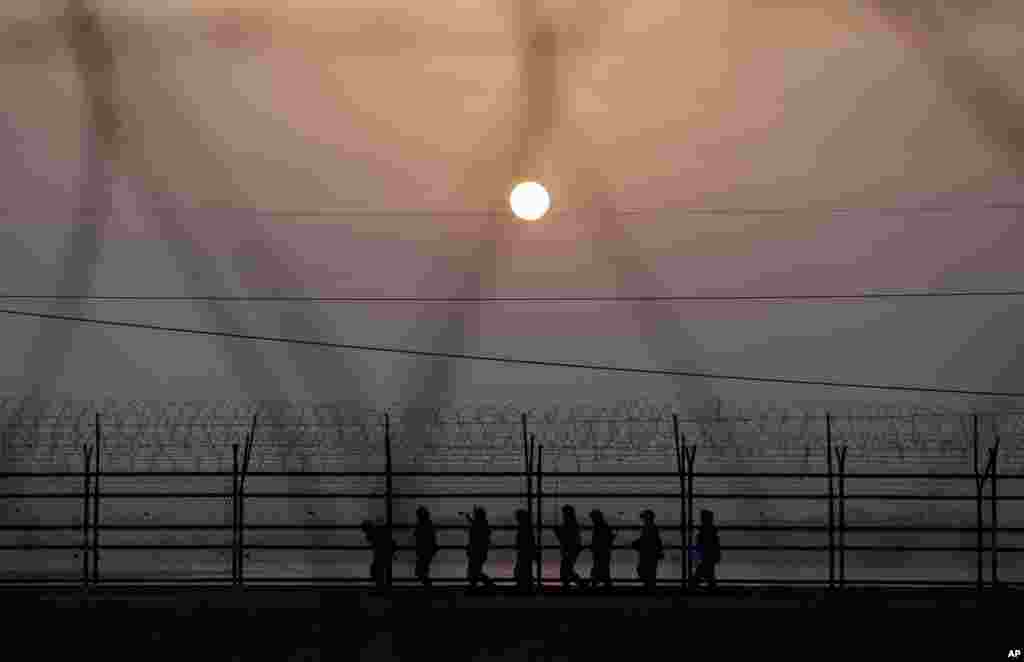 South Korean army soldiers patrol along a barbed-wire fence at sunset near the border village of Panmunjom, which has separated the two Koreas since the Korean War, in Paju, north of Seoul. Busloads of tourists still show up to gawk at the world's most heavily fortified border.