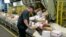 FILE - Steve Robino arranges packages on a conveyor belt at the main post office in Omaha, Neb., Dec. 14, 2017.