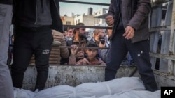 A boy looks at the bodies of Palestinians killed in the Israeli bombardment of the Gaza Strip as they are brought for burial at Al-Aqsa Hospital in Deir al-Balah, Jan. 15, 2025.