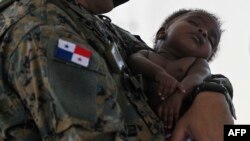 En esta foto de archivo tomada el 09 de febrero de 2021, un miembro del Servicio Nacional de Fronteras carga a un niño migrante en la Estación de Recepción de Migrantes (SRM) en Lajas Blancas, provincia de Darién, Panamá.