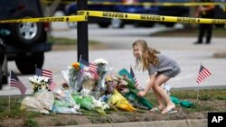 Una niña deja un ramo de flores en un altar dedicado a las víctimas del tiroteo en Virginia Beach, al filo de un cordón policial frente al edificio municipal donde ocurrió la tragedia. Enero 1, de 2019.