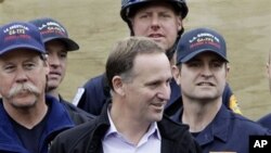 New Zealand's PM John Key, center, meets with relief workers from US during a tour of a tent city where hundreds of international and local relief workers have been housed in central Christchurch following Tuesday's earthquake in New Zealand, February 26,