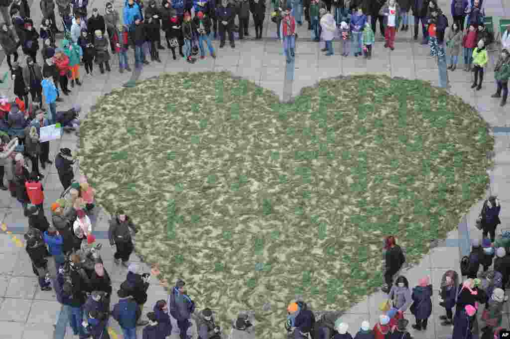 People surround a green heart made of small branches to expressing their feelings towards the Bialowieza forest, considered the last primeval forest on the European plain, during an event on Valentine&#39;s Day, in Warsaw, Poland.