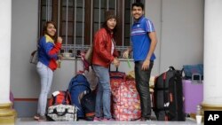 Venezuelan migrants wait outside their country’s embassy for a bus that will transport them to the airport, in Lima, Peru, Monday, Aug. 27, 2018. 